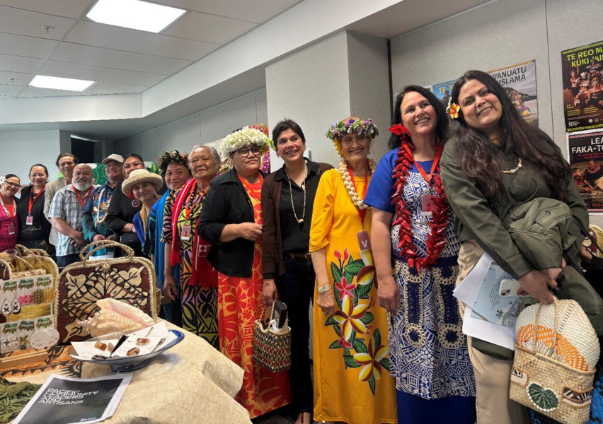 A group of 15 people in a row, wearing pacific attire and smiling
