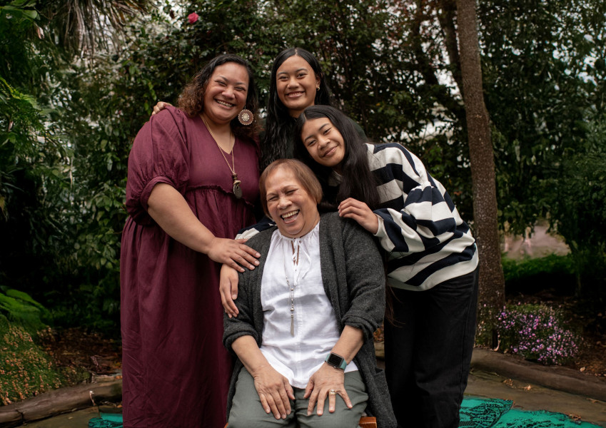 A group of four people with their arms around each other and smiling. They are standing outside